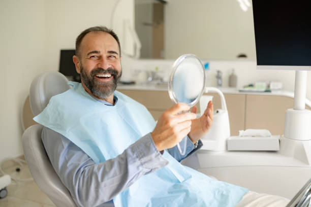Patient souriant découvrant son nouveau sourire dans un miroir